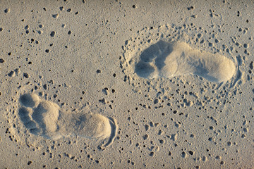 Close-up of footprint of child`s pair of feet on the sand.