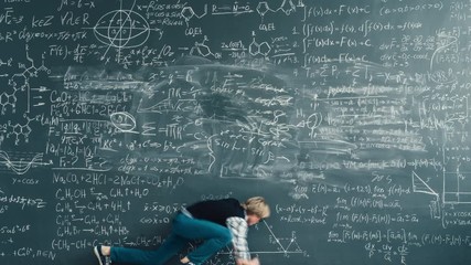 Zoom-in time-lapse of smart person solving scientific problem writing formulas on chalkboard focused on studies. People and knowledge concept.