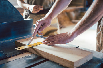 Close-up on hand of carpenter marking a cut with pencil