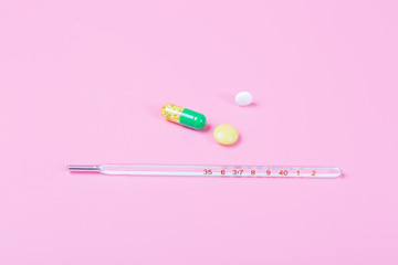 Syringe and miniature human and oral medicine and thermometer macro closeup on pink background