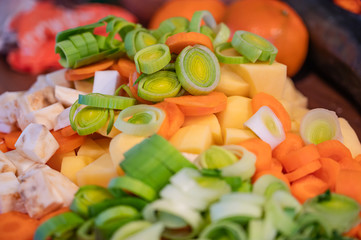 Fresh vegetables cut into small pieces with a knife on a cutting board