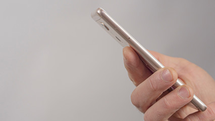 Close-Up Of Male Hands Holding A Mobile Phone. Man Uses A Mobile Phone. High Quality Photo