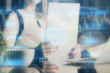 Double exposure of hands making notes with forex chart huds. Stock market concept.