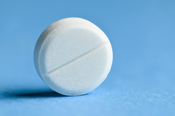One white pill on blue background macro photo - concept of medicine and medication treatment,...
