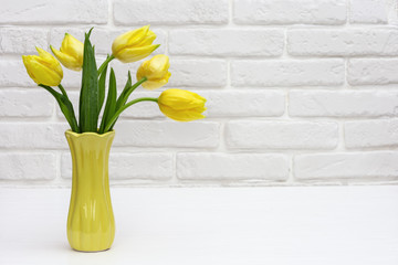 Spring flowers of tulip in vase on decorative brick wall.  Natural flowery background with copy space.  Bright colors.