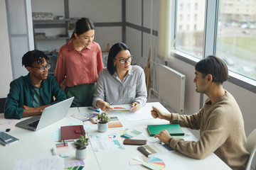 Young business leader talking to his business team and they listening to him attentively during meeting at office