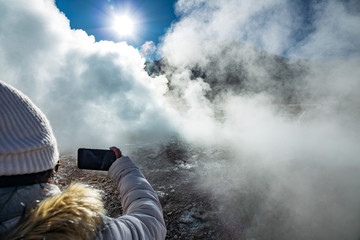 Unrecognizable tourist taking photos to active Geyser heap