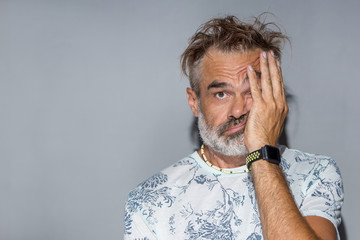 Confused man with funny messy hair. Indoor portrait of handsome man with grey beard and hair