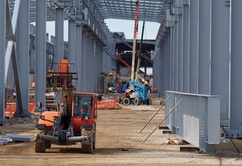 Telescopic handler at work inside a large a large industrial building under construction. Other...