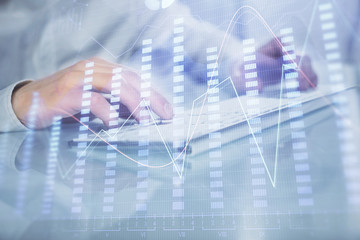 Double exposure of graph with man typing on computer in office on background. Concept of hard work. Closeup.