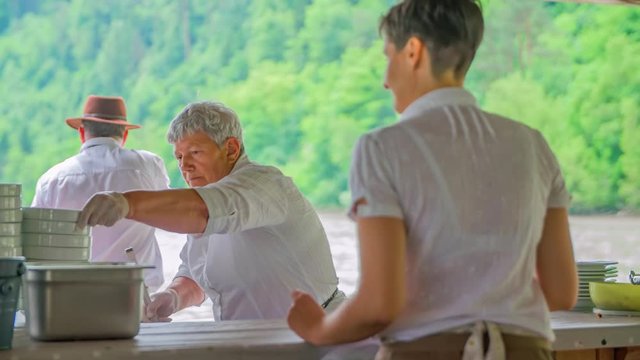 Senior waitress scoop goulash soup on River Drava raft Muta, Slovenia