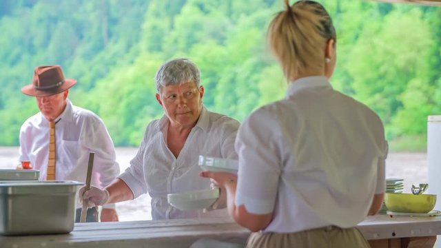Slovenian waitress serve goulash soup on Drava raft kitchen Muta, Slovenia