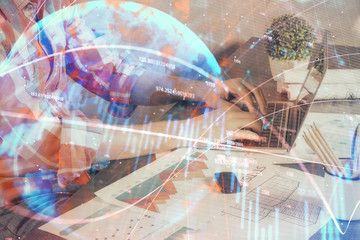 Double exposure of stock graph with businessman typing on computer in office on background. Concept of hard work.