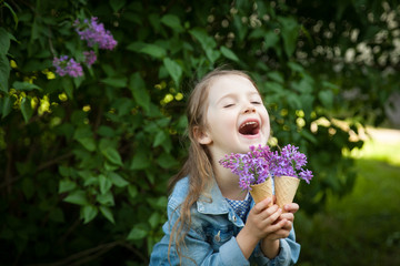 Little girl with waffle ice cream cone filled with lilac flowers in her hands