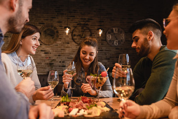 Group of young friends having fun in restaurant, talking and laughing while dining at table.