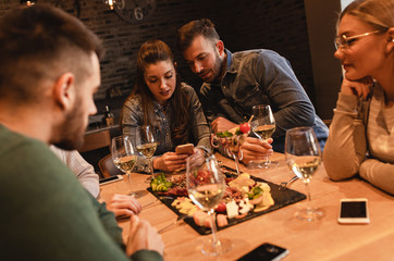 Group of young friends having fun in restaurant, talking and laughing while dining at table.