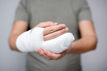 first aid concept - close up of male hand with bandage and gypsum