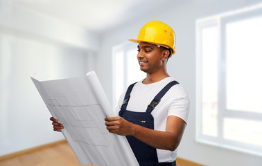 profession, construction and building - happy smiling indian builder in helmet with blueprint over empty room at new home or apartment background