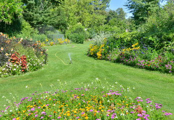 Obraz premium spreakler watering lawn in a lanscaped park in summer