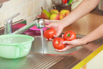 woman washing fresh vegetables in kitchen