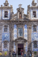 Fototapeta na wymiar Ildefonso church with tourists in Porto, Portugal. Traditional portuguese exterior with ceramic azulejo tiles. Ancient church in baroque style. Religious architecture. 