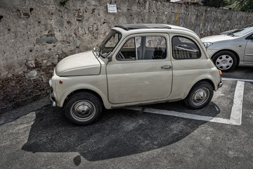 Old Fiat 500 car in front of an old stone wall in Italy Pisa Tuscany