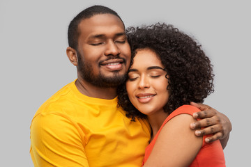 relationships and people concept - happy african american couple hugging over grey background