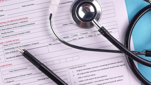 Health insurance claim form, stethoscope and pen on a light-blue background. Close-up
