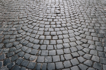 The gray paving stones laid out in a semicircle. The texture of the old dark stone. Road surface. Vintage, grunge.