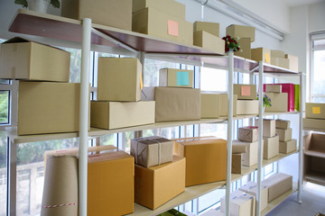 Wrapped cardboard parcel boxes on storage shelf in workplace - Online selling, e-commerce and SME concept 