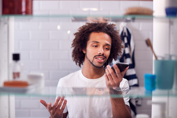 View Through Bathroom Cabinet Of Businessman Using Mobile Phone To Practise Presentation