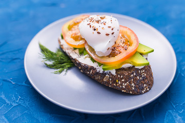 Sandwich with smoked salmon, egg and avocado on blue background, top view. Concept for healthy nutrition.