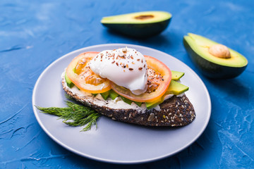 Sandwich with smoked salmon, egg and avocado on blue background. Concept for healthy nutrition.