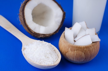 Natural coconut milk, coconut shavings, coconut chips on a blue background. The concept of healthy food.