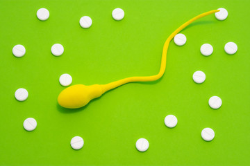 3D anatomical model of sperm cell or spermatozoon is on green background surrounded by white pills...