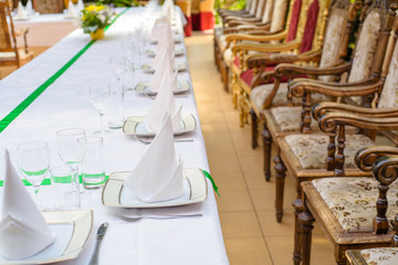 Long served table with plates, glasses, napkins and chairs