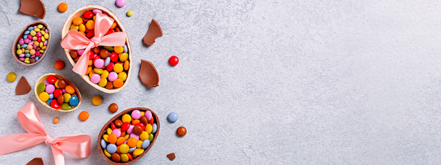Chocolate Easter eggs and candy on concrete table, festive Easter background web banner, copy space. Easter card with traditional Easter treats on grey table top. Sweet Easter concept