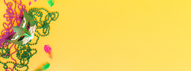 Mardi gras accessories web banner on bright yellow background, top view, copy space. Frame with...