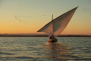 Old style sailing boat in the lake in sunset