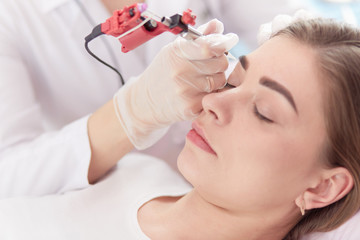 A young girl having red lips permanent makeup, micropigmentation