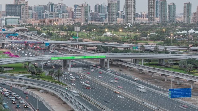 Dubai Golf Course with a cityscape of Gereens and tecom districts at the background aerial day to night transition timelapse. Traffic on sheikh zayed road with junction