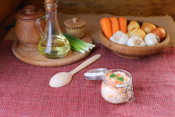 Glass jar of sauerkraut by the plate of vegetables on the kitchen table. 
