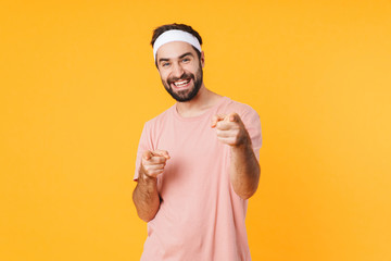 Image of muscular athletic young man smiling and pointing fingers