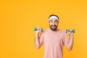 Image of muscular athletic young man having fun and lifting dumbbells
