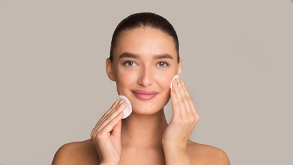 Face care. Girl using cotton pad over grey background © Prostock-studio