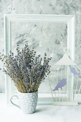 Tender still life. Lavender flowers in a cup, frame and decorative birds in a cage. Vintage provence style.