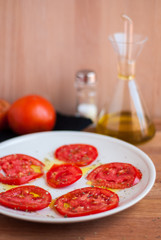 Plato con rodajas de tomate aliñado sobre tabla de madera