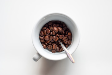 Taza vista desde arriba llena de granos de café sobre fondo blanco