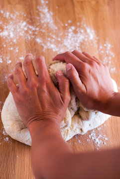 Manos de mujer amasando pan sobre madera