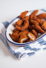 Bandeja de fingers de pollo sobre servilleta y fondo blanco